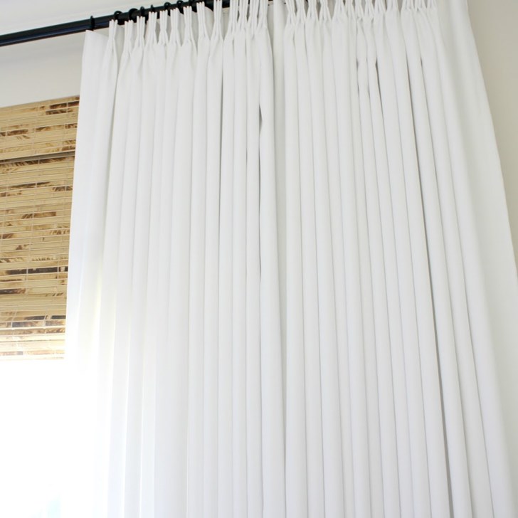 Customer Shelley gave her bedroom privacy and texture with Budget Woven Wood Shades in Antigua Natural and Easy Classic Pleat Panels in Lexi White. Photo via Crazy Wonderful